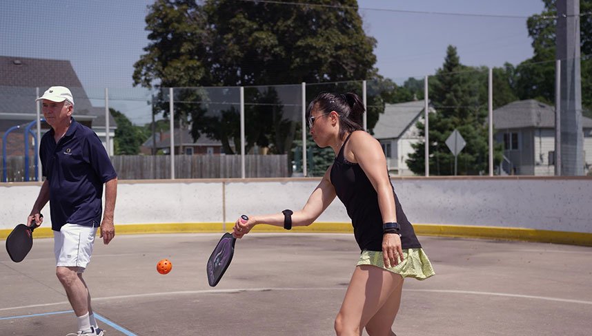 two adults participating in a game of pickleball on an outdoor court